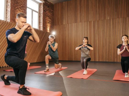 Adults practicing exercises on yoga mats in a contemporary studio setting.