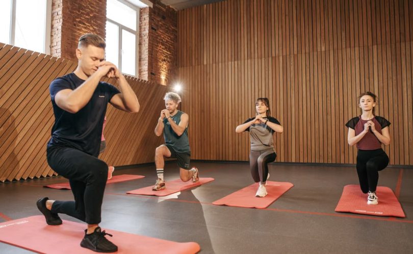 Adults practicing exercises on yoga mats in a contemporary studio setting.