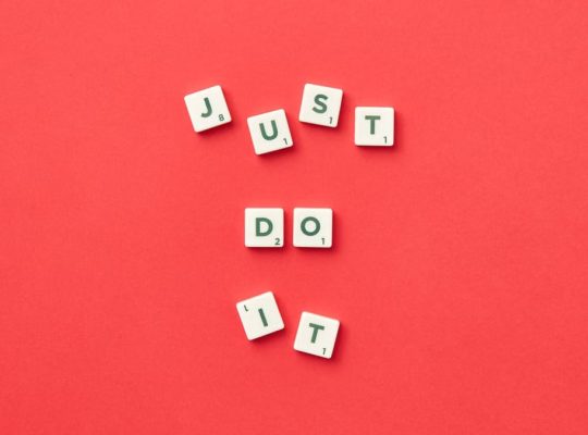 Motivational phrase 'Just Do It' spelled with Scrabble letters on a red background.