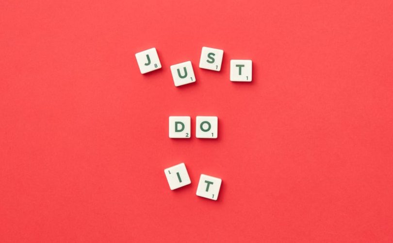 Motivational phrase 'Just Do It' spelled with Scrabble letters on a red background.